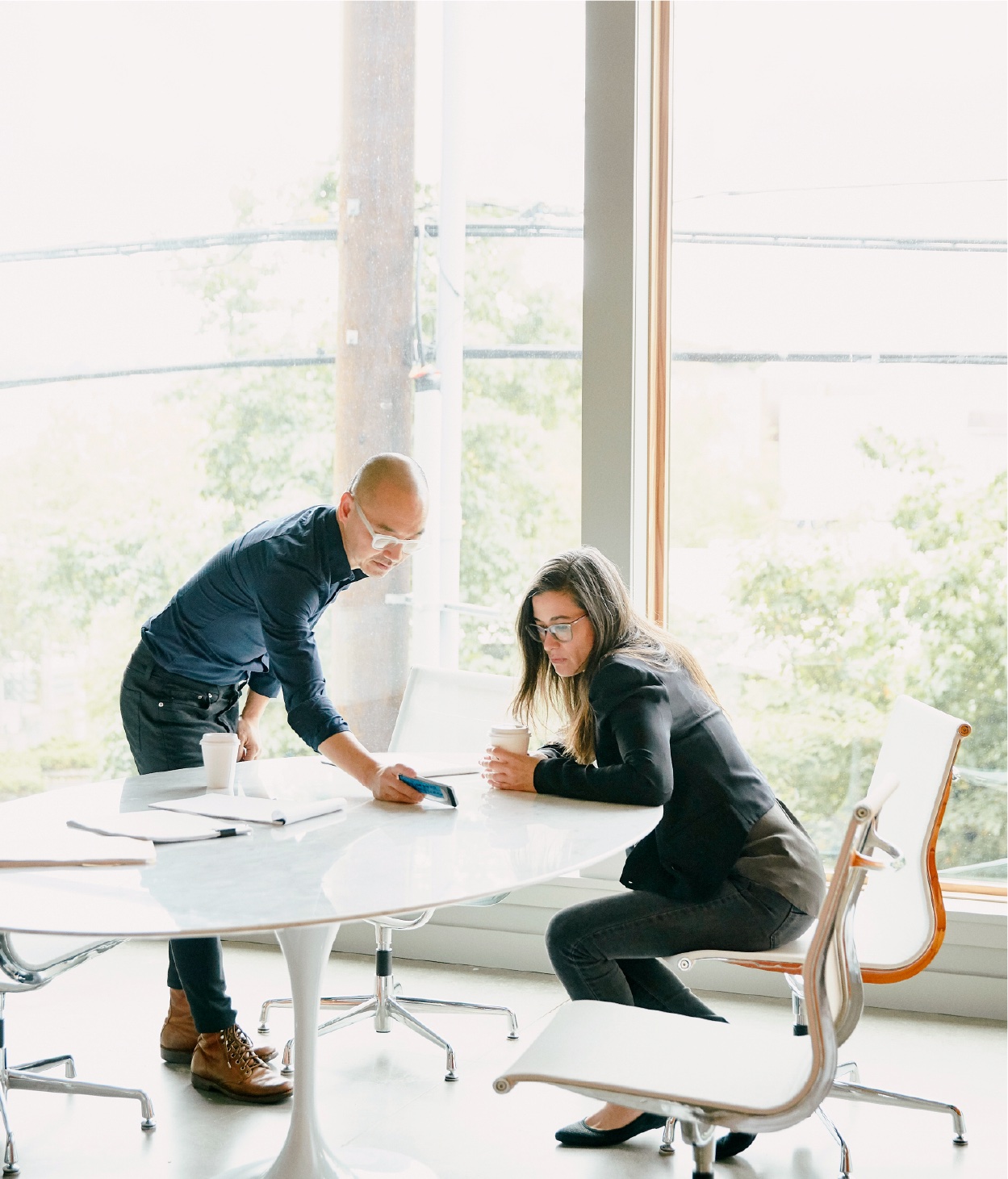 Dos compañeros discuten sobre un proyecto de trabajo con sus móviles.